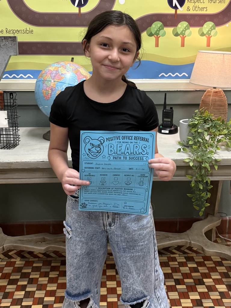 student standing with a positive office referral paper