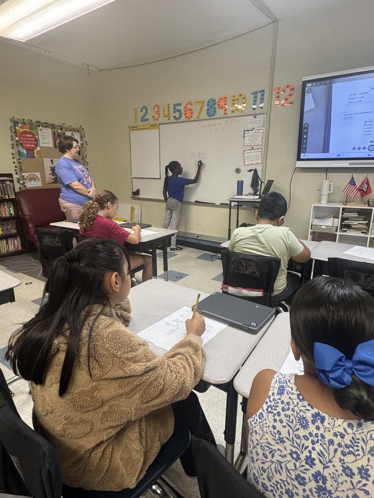 a student leading classmates through a problem on the board.