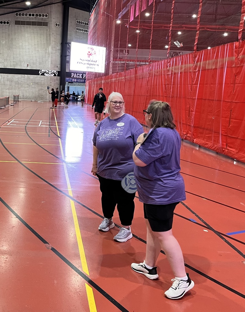 Two El Dorado School District educators talk on the court while holding pickleball paddles during Special Olympics Arkansas RecFest.