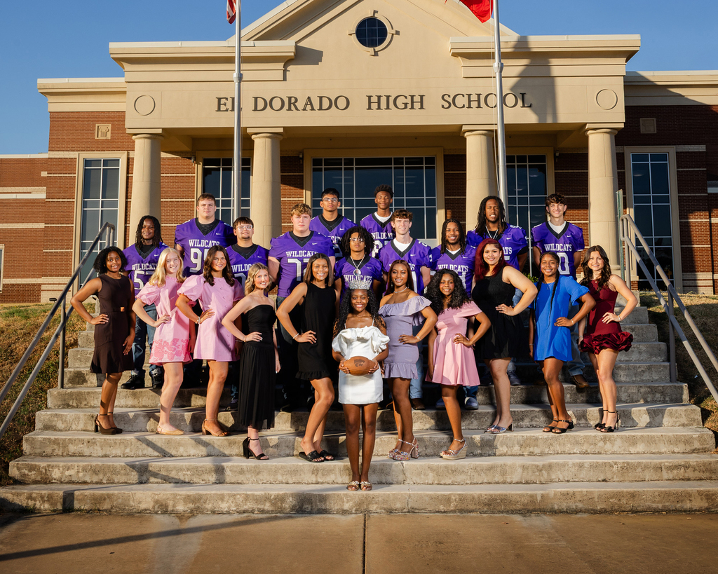 Group photo of El Dorado High School students posing on the front steps of the school. Football players in purple Wildcats uniforms stand behind students dressed in formal attire, with one student in front holding a football.