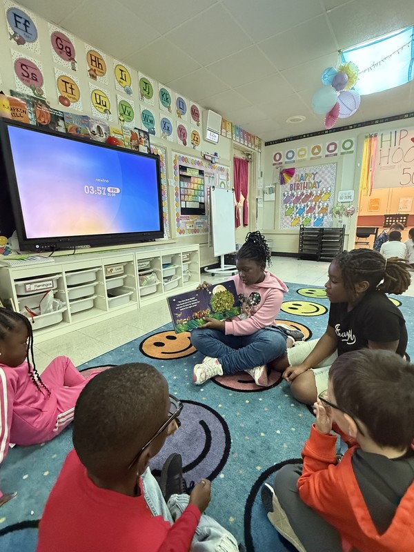 2 girls reading to 3 kinders