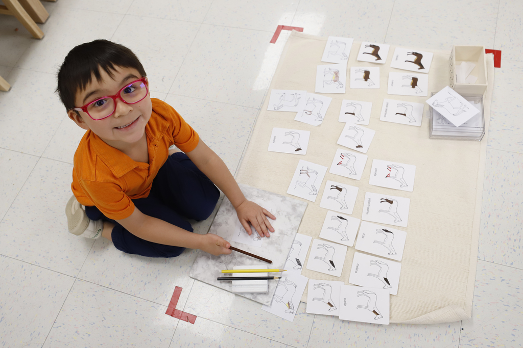 Child working on a project and smiling up at the camera