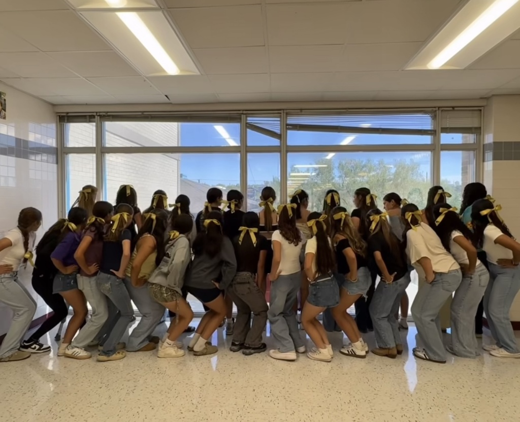 Students showing gold bows on the back of their heads for a group photo for Childhood Cancer Awareness Month