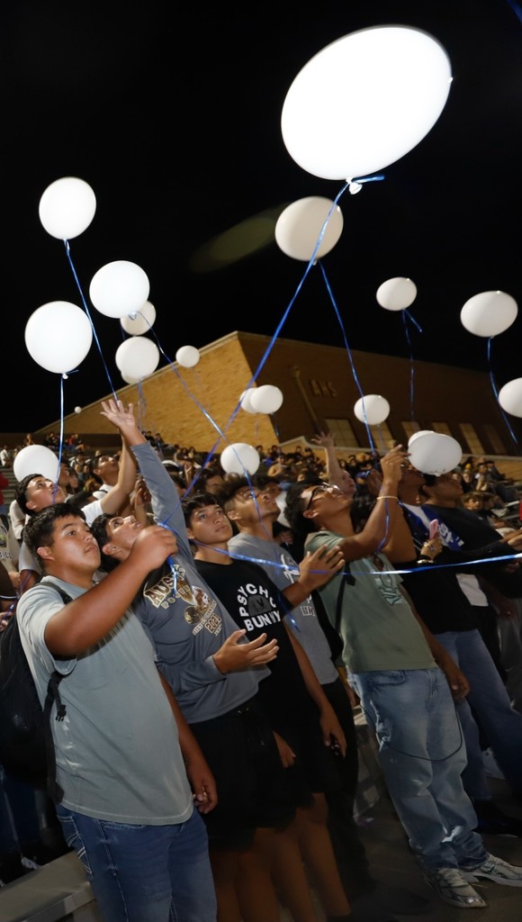 Students hold onto white balloons