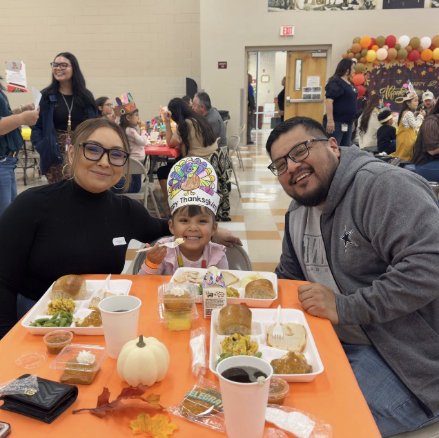 Parents take photo at thanksgiving luncheon with their daughter