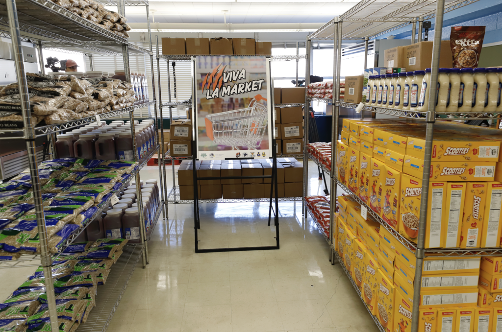 Photo inside the Lamar Family Resource Center. Food pictured and sign that says Viva La Market
