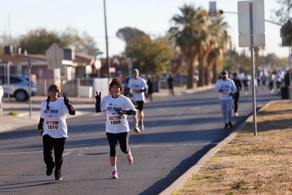 Community members smile and do peace sign while running at the El Paso ISD Education Foundation Fast Track to the Future 5K