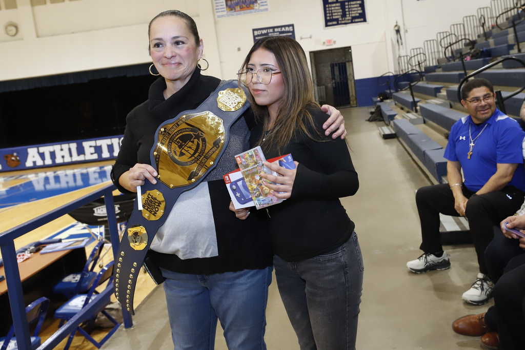 Bowie High School principal takes photo with student who won a Nintendo Switch for perfect attendance and also shows off Bowie High School's Attendance Championship Belt