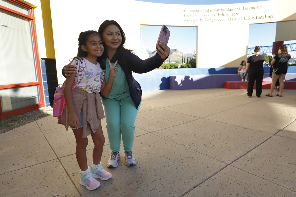 Mom and daughter take a photo in front of Whitaker Elementary School before school begins