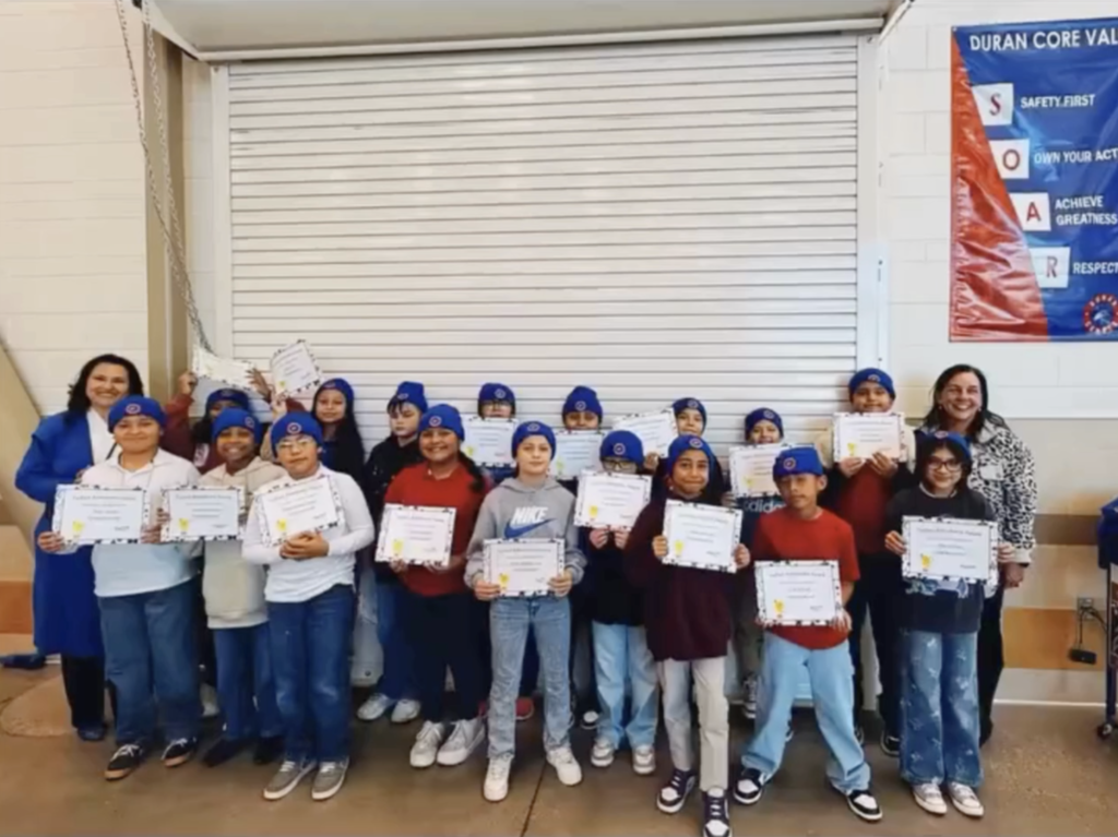 Duran Elementary School students celebrate perfect attendance with certifications and new campus beanies while taking a group photo