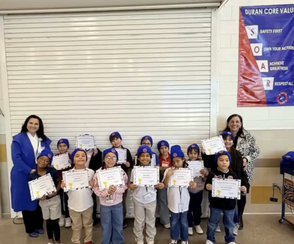 Duran Elementary School students celebrate perfect attendance with certifications and new campus beanies while taking a group photo
