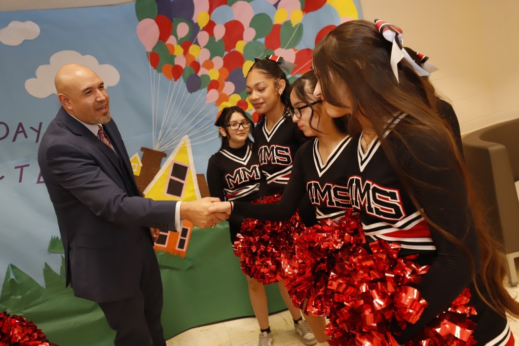 Trustee Alex Cuellar shakes hands with MacArthur PK8 cheerleaders