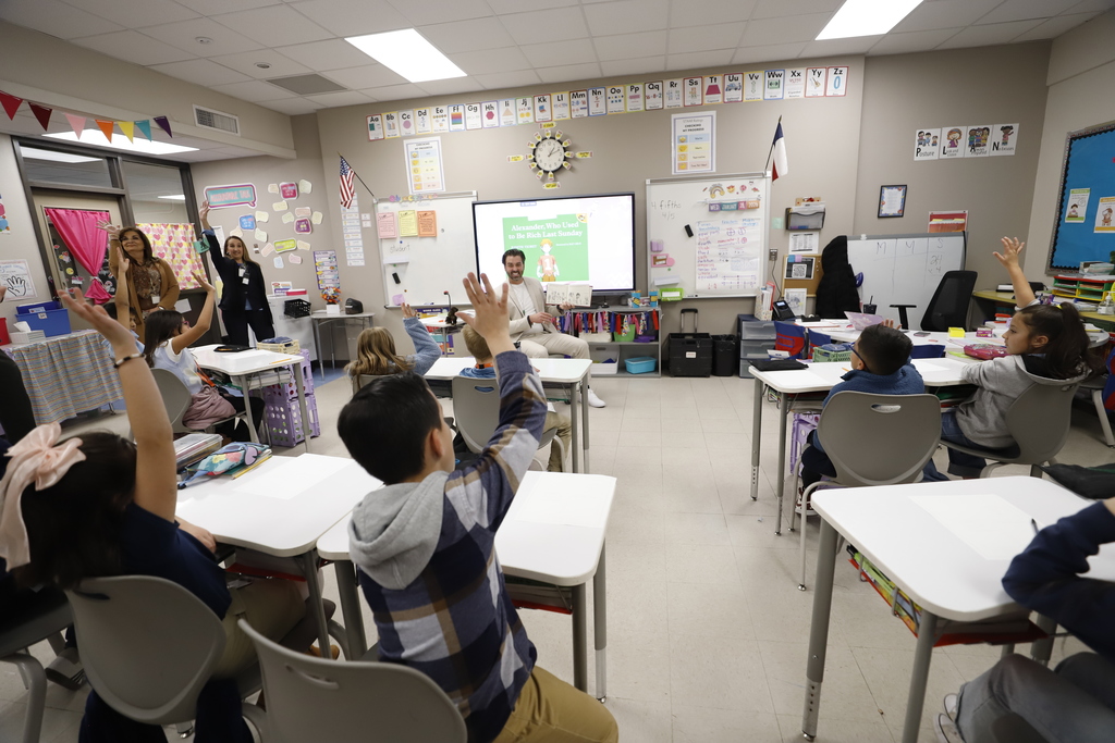 Trustee Daniel Call reads to students as they raise their hands