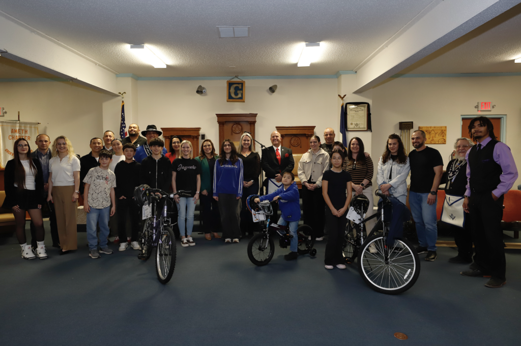 Large group of students and parents take a photo with new bike and El Paso ISD staff at the DODEA Bicycle Donation Dinner