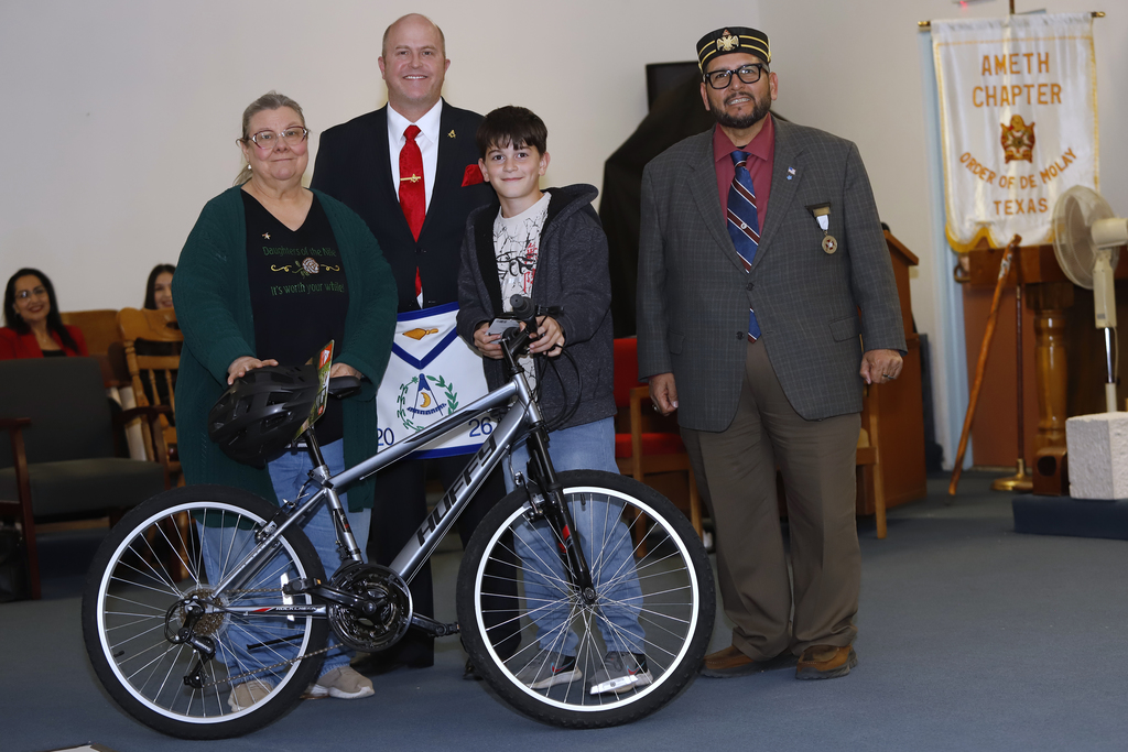 Student and parent take photo with new bike and El Paso ISD staff at the DODEA Bicycle Donation Dinner