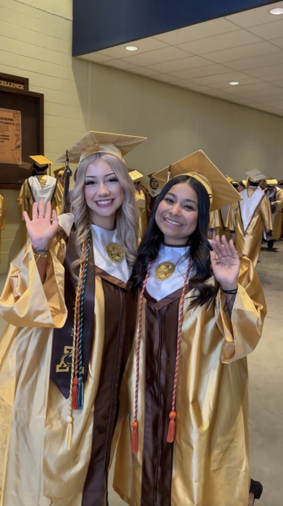 Two Austin High School graduates smiling and wave at camera