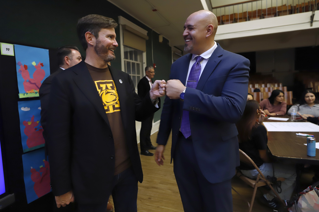 Trustee Dr. Jack Loveridge and Truste Alex Cuellar smile while fist bumping