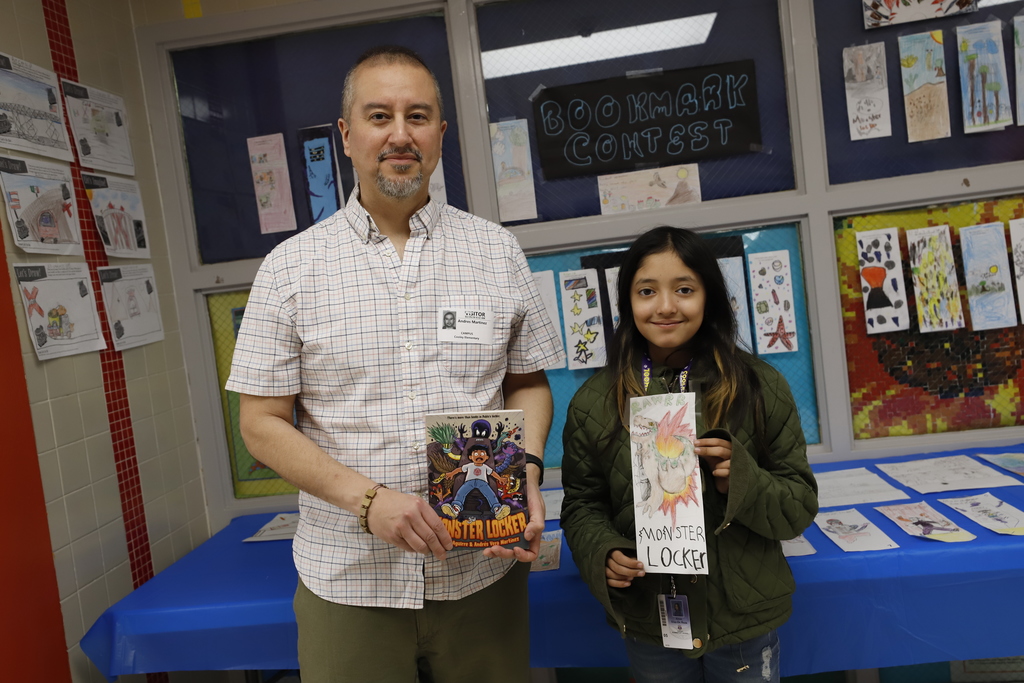 Illustrator and student smile together for a photo holding Monster Locker book