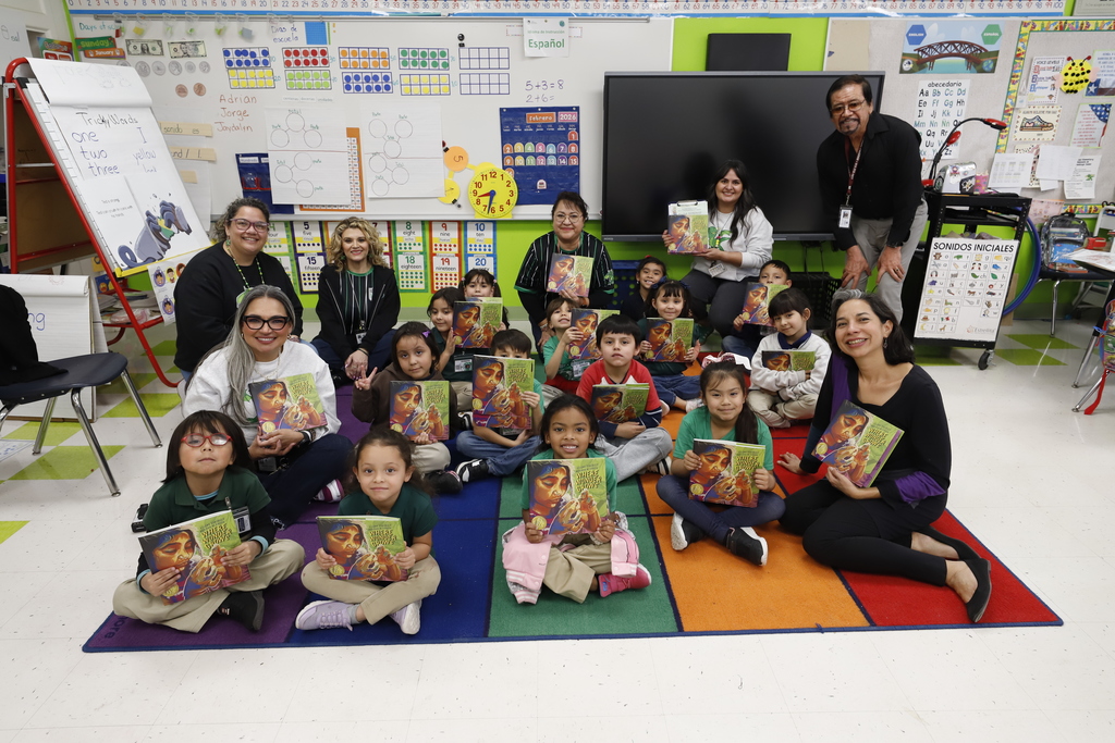 Douglass Elementary students and staff smile for a group photo with author while holding new books 
