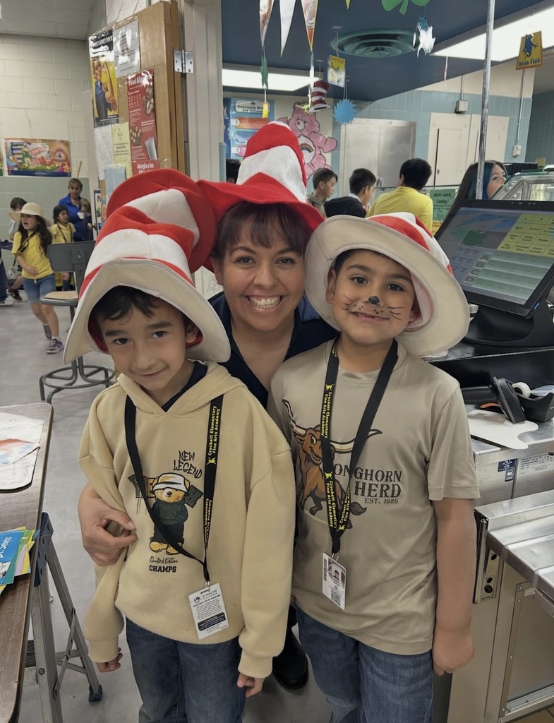 Students and teacher smile for a photo while wearing Dr. Seuss hats