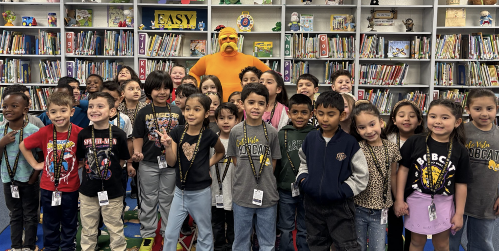 Students and teacher smile for a group photo while teaching wear the Lorax costume
