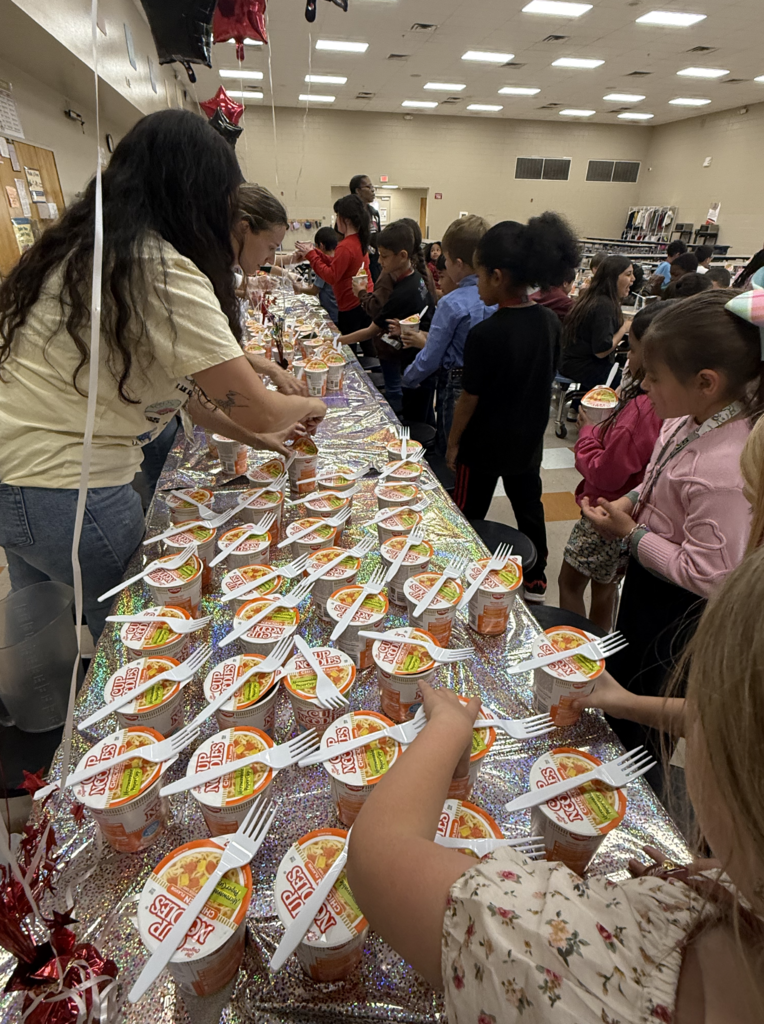 A line forms as Tom Lea staff sets up table full of ramen noodles