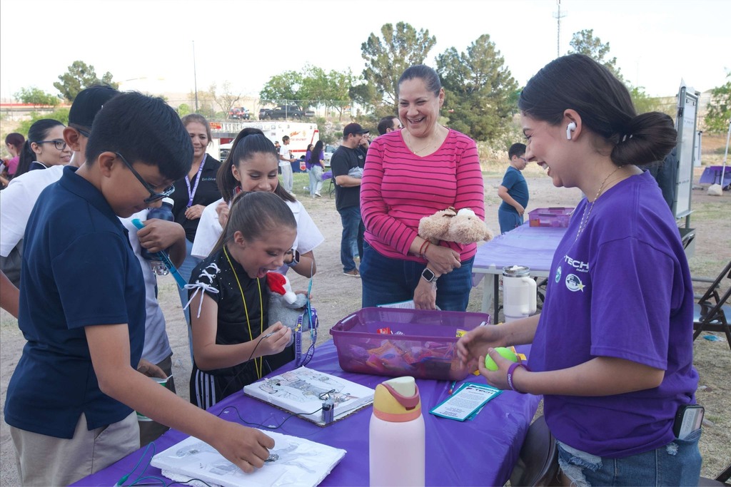 Students and parents smile at information table with Franklin P-TECH student