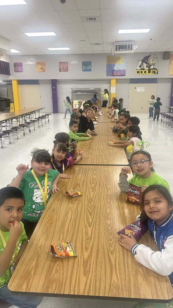 Students smile for camera in the cafeteria while eating Hot Cheetos with cheese