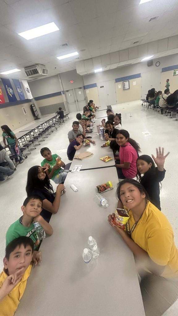Students smile for camera in the cafeteria while eating Hot Cheetos with cheese