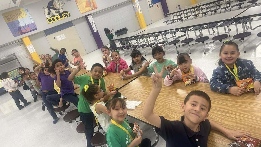 Students smile for camera in the cafeteria while eating Hot Cheetos with cheese