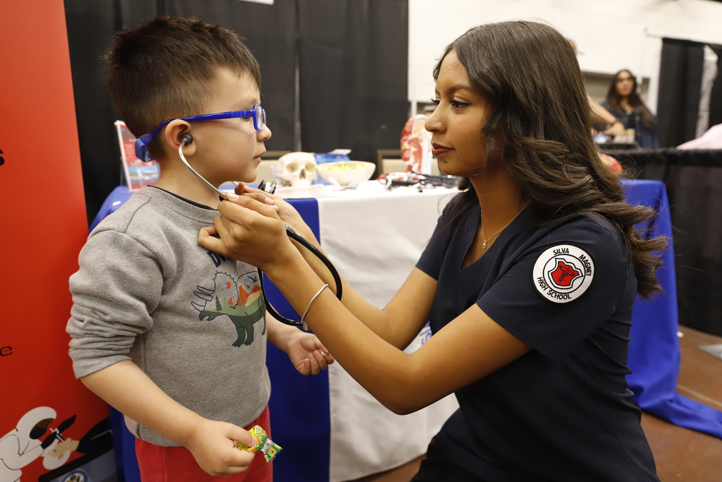 Jefferson Silva students puts stethoscope on young child so he can listen to his heartbeat