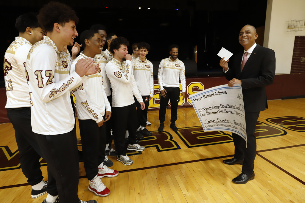 Mayor Renard Johnson laughs with the Andress High School boys basketball team while presenting them  giant check