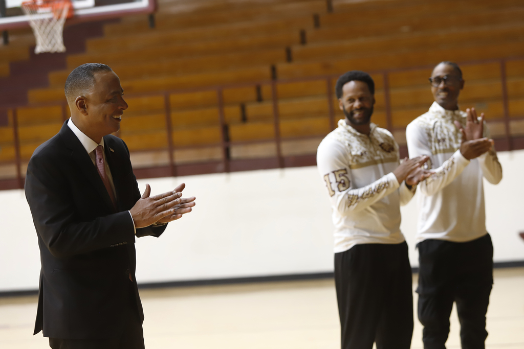 Mayor Renard Johnson and Andress High School basketball coaches smile while clapping