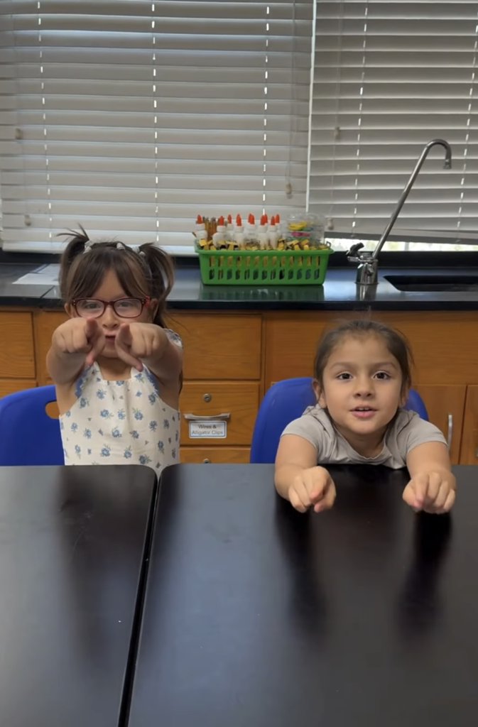 Two young students pointing at the camera