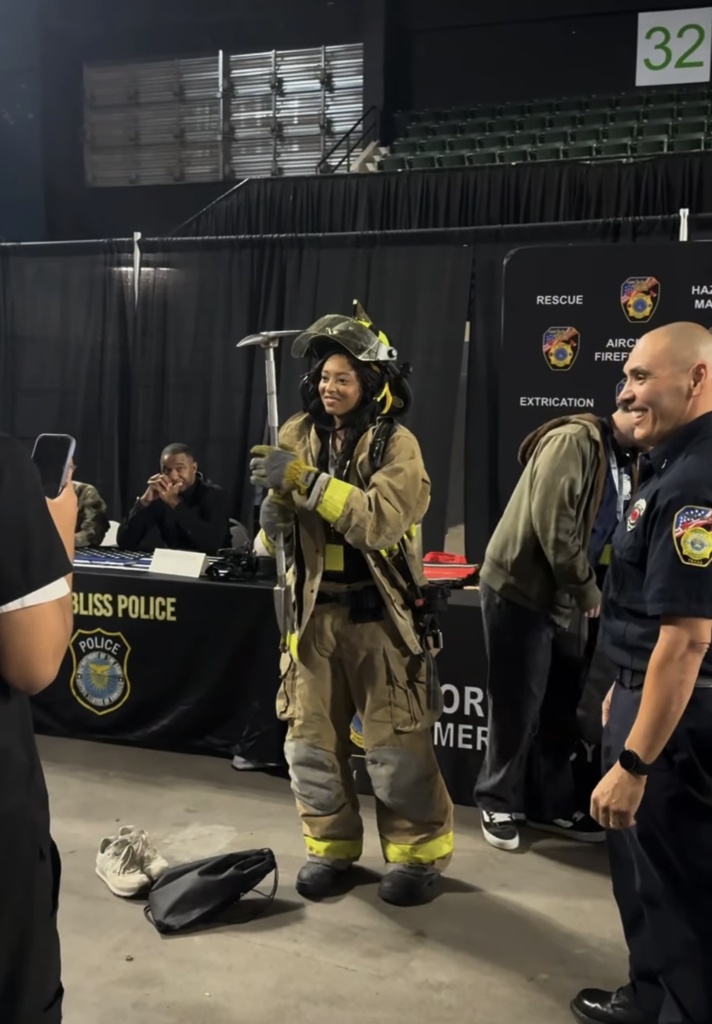 Student tries on firefighter gear and holds pickaxe