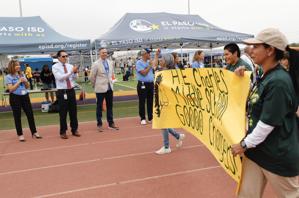 Charles Middle School students walk on track during Unidos Games parade while EPISD staff cheers them on