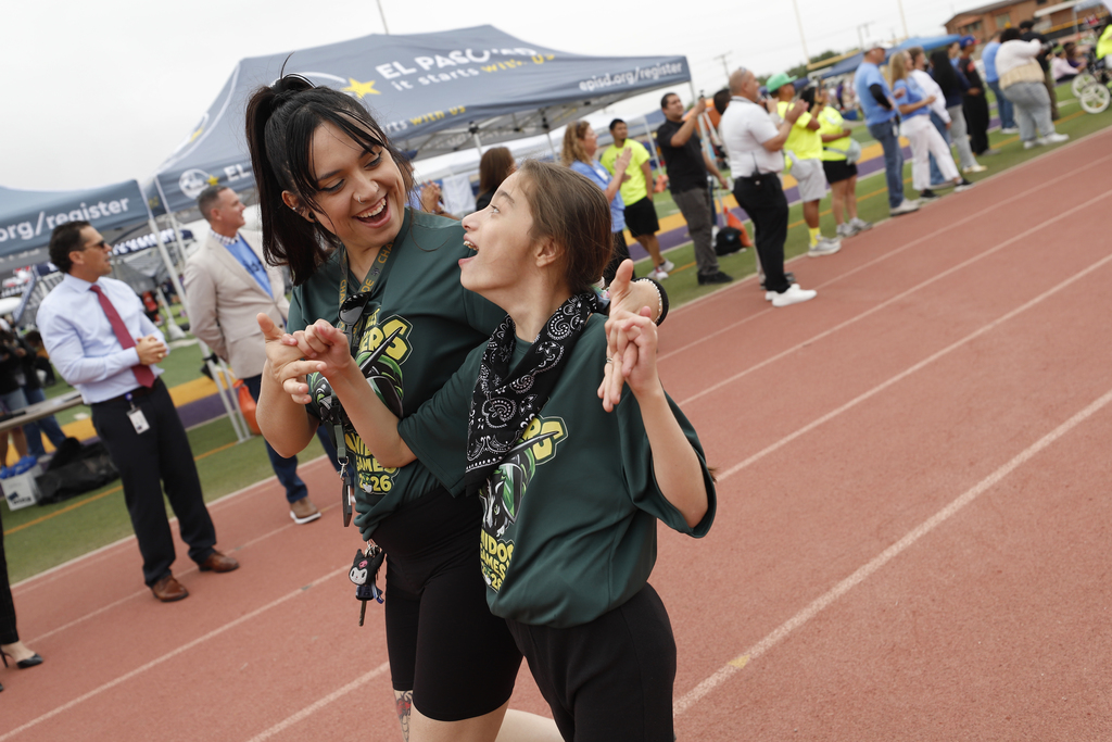 Charles Middle School student and staff member walk on track during Unidos Games parade