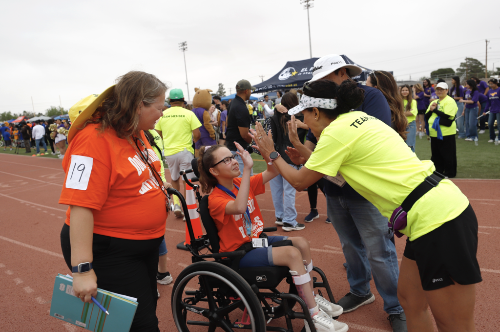 Staff member high fives student after racing at the Unidos Games