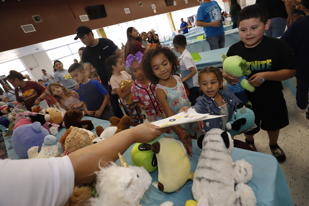 Student reach for paper in front of table full of stuffed animals