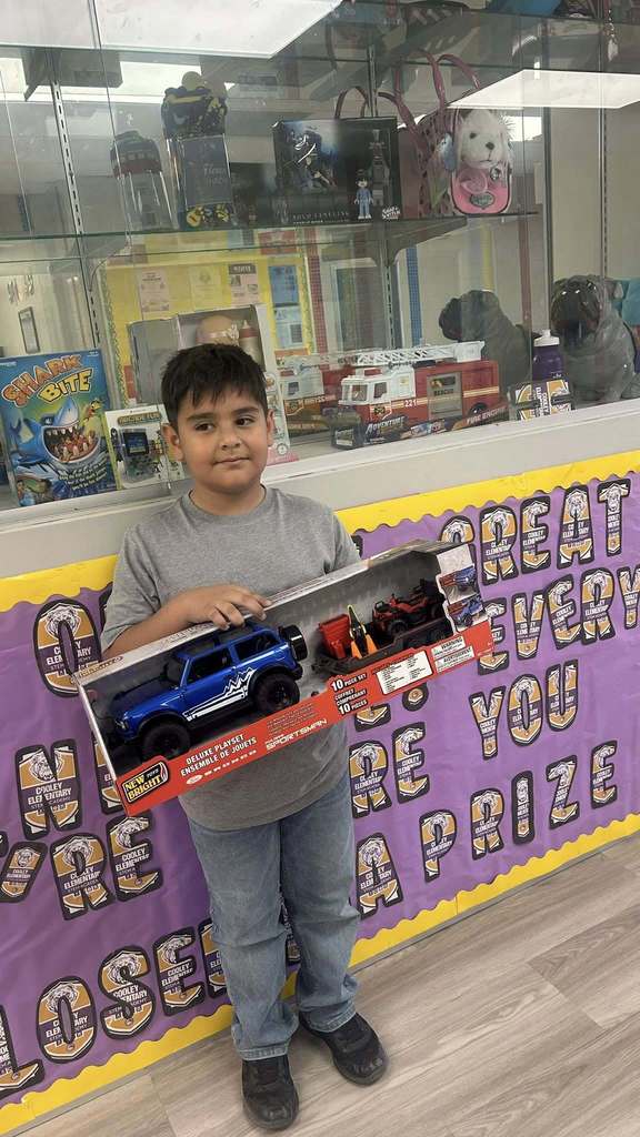 Students holds car toys as part of prize for perfect attendance