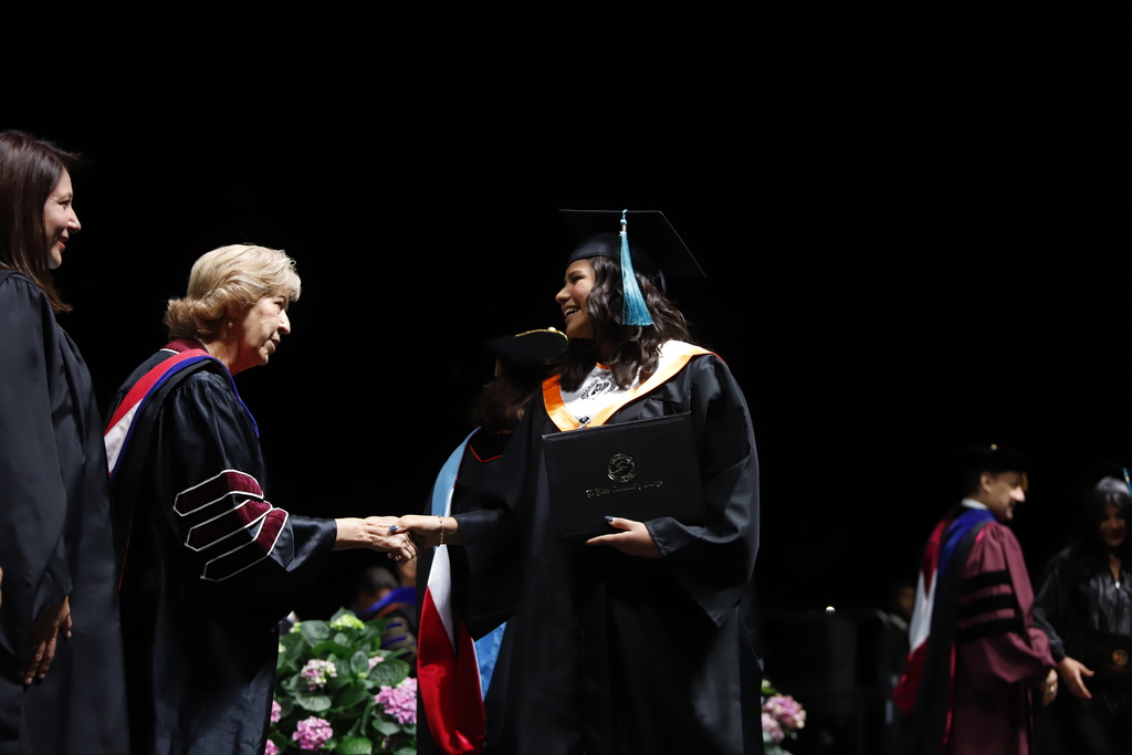 El Paso High School graduate shakes hands with EPCC staff after receiving diploma