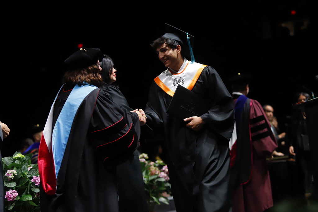 El Paso High School graduate shakes hands with EPCC staff after receiving diploma