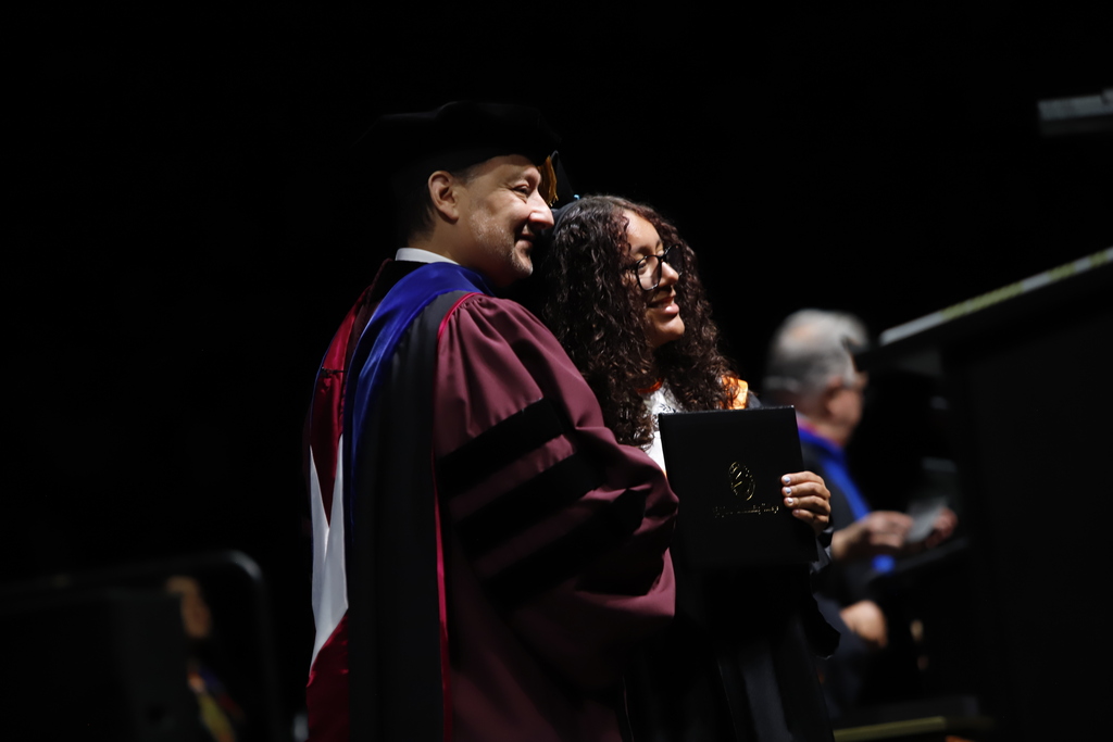 El Paso High School graduate takes photo with diploma and EPCC President after receiving diploma