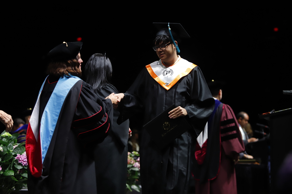 El Paso High School graduate shakes hands with EPCC staff after receiving diploma