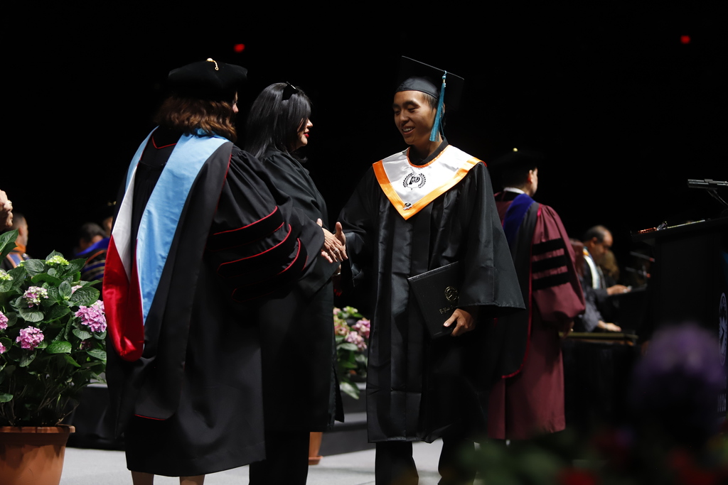 El Paso High School graduate shakes hands with EPCC staff after receiving diploma