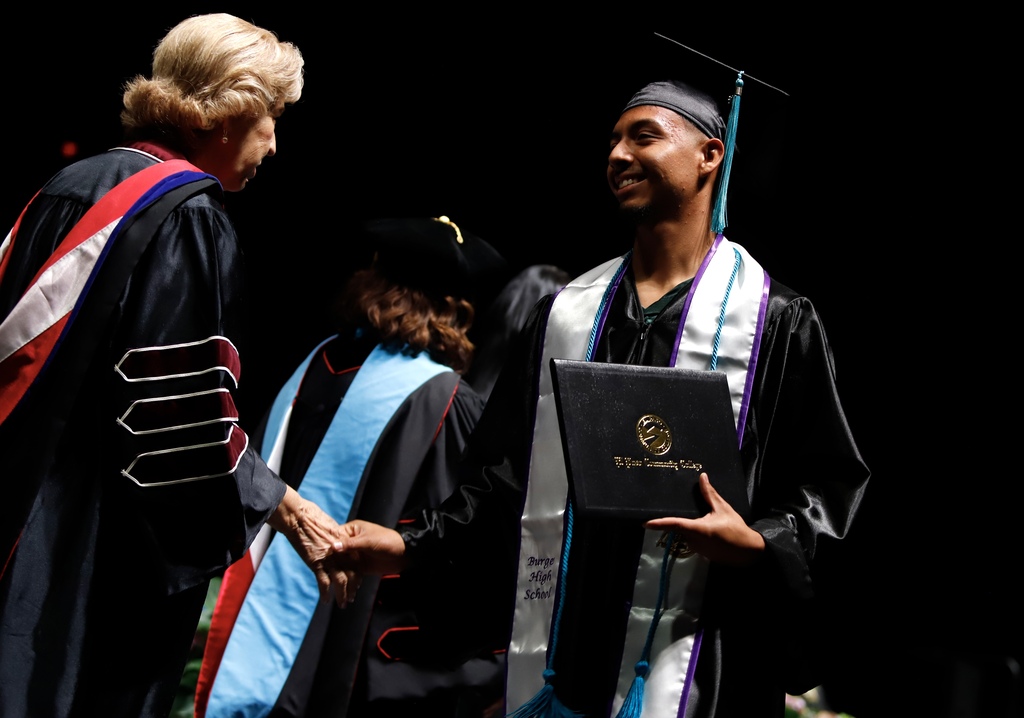 Burges High School student shakes hands with EPCC staff member after receiving diploma