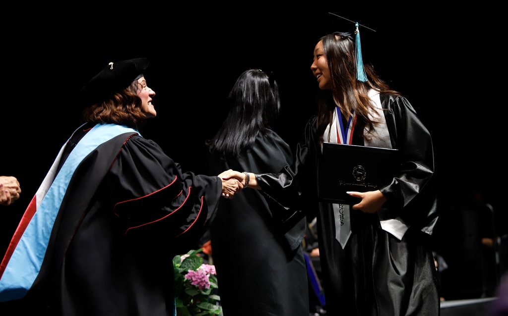 Transmountain Early College High Schoo graduate shakes hands with EPCC staff after receiving diploma
