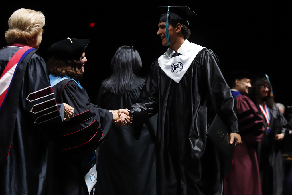 Coronado High School P-TECH student shakes EPCC staff members hand while after diploma