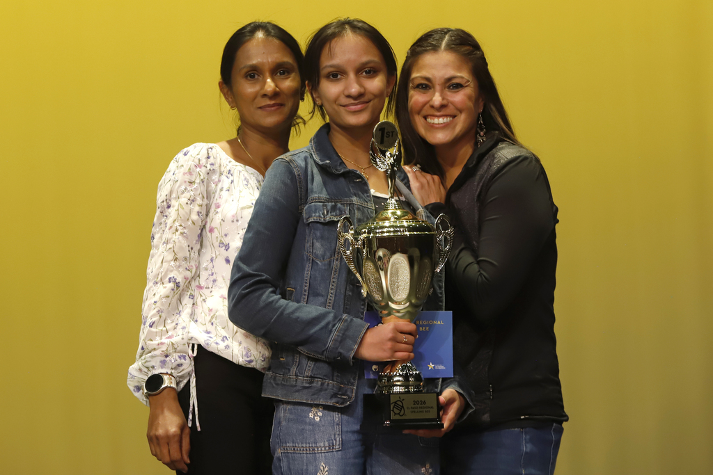 Shaheli De Silva, Young Women's STEAM Prep Academy smiles with family while holding spelling bee trophy