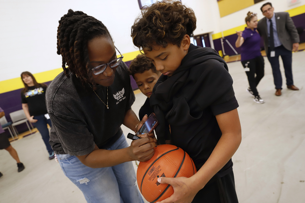 A&A All the Way Foundation member helps sign basketball for Hartley PK-8 Student